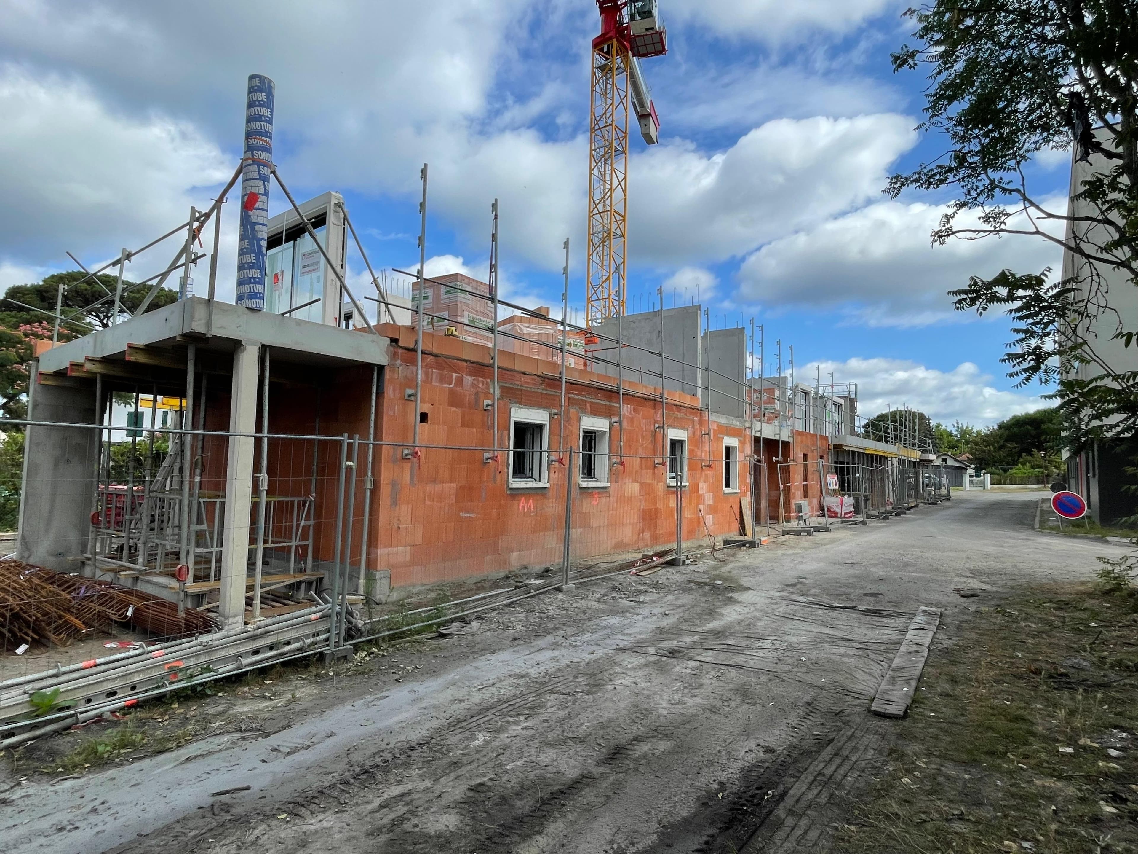 Élévation des murs en briques avec ouvertures pour fenêtres sous grue - Aurès Construction