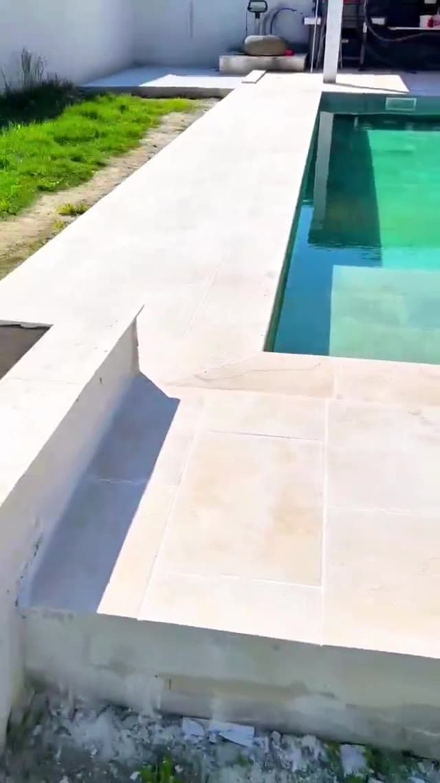 Piscine terminée avec plage en pierre et eau turquoise - Aurès Construction